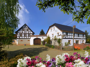 Historischer Vierseitenhof mit Fachwerkhäusern und Torbogen in Waldsachsen, vorn blühende Petunien