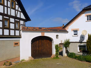 Hoftor mit Rundbogen und Holztor zwischen zwei Fachwerkhäusern
