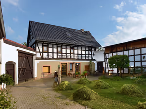 Innenhof der Pension mit Fachwerkhaus, Sitzplatz und Blumen